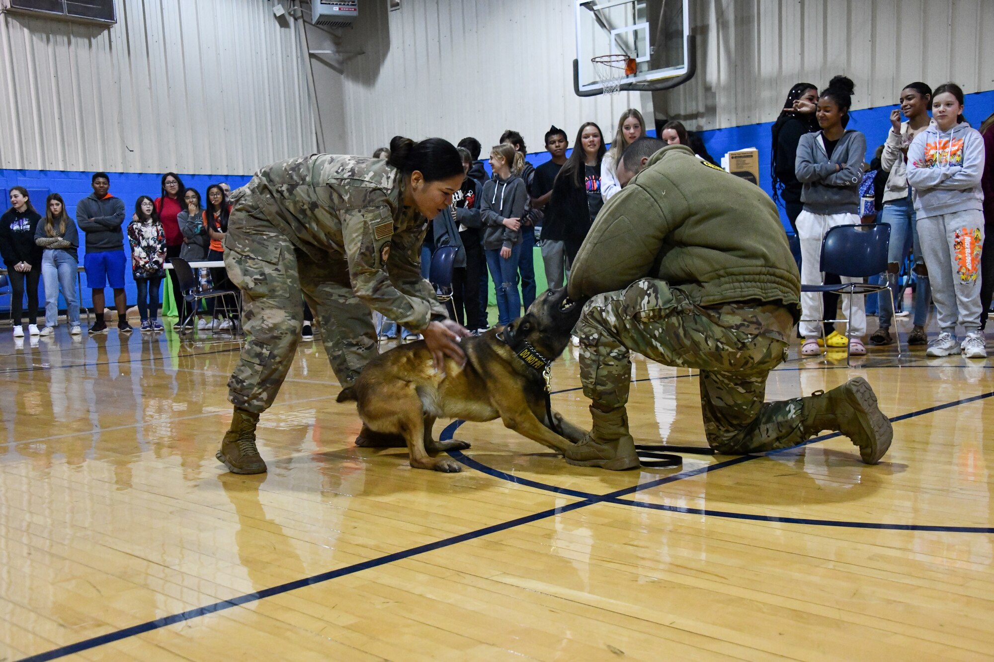 From left, Staff Sgt. Destiny Savini and Tech. Sgt. Andres Posada, 97th Security Forces Squadron (SFS) military working dog handlers, demonstrate threat neutralization at Altus High School, Altus, Oklahoma, March 30, 2022. Military working dogs are trained for many purposes such as tracking, attacking, search and rescue missions and detecting explosives. (U.S. Air Force photo by Airman 1st Class Miyah Gray)