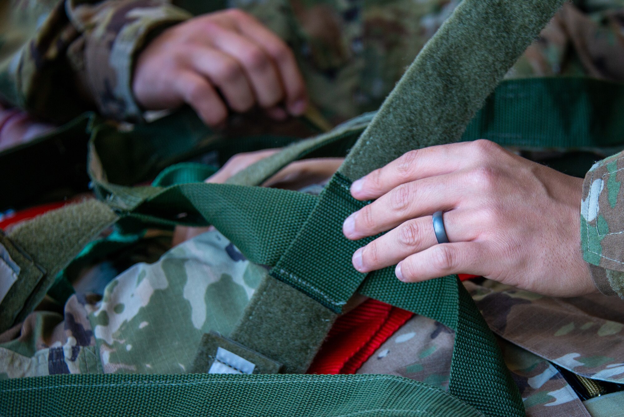 close up of Airmen securing a simulated patient to a backboard