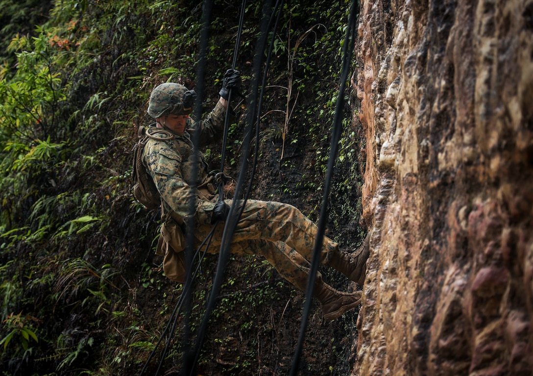 U.S. Marine Corps Capt. Thomas DeVries, the operations officer for Communication Strategy and Operations Company, III Marine Expeditionary Force Information Group, rappels down a cliff during an instructional course at Jungle Warfare Training Center, Camp Gonsalves, Okinawa, Japan, March 23, 2022. The rappelling was conducted as part of an overall Jungle Field Exercise conducted on March 21-25.