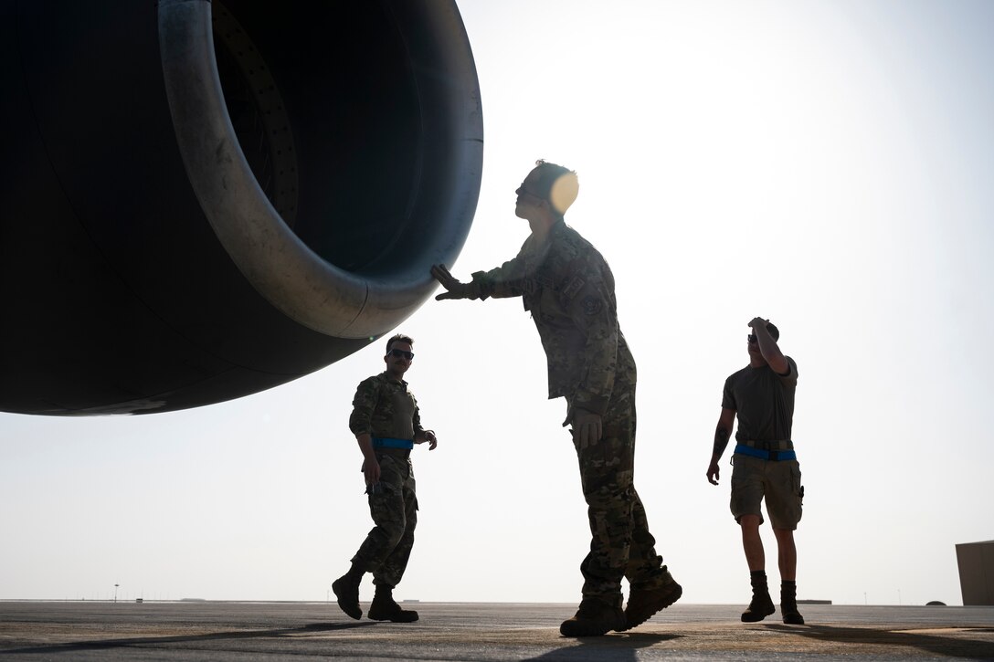 An airman looks inside a jet engine.