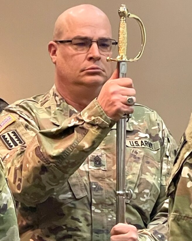 U.S. Army Command Sgt. Maj. (CSM) Joseph Gregory, Fort Custer Training Center- Garrison, Michigan Army National Guard, receives the noncommissioned officers sword and presents it to CSM Jay Bennett, command sergeant major to the assistant adjutant general-Michigan Army National Guard, during a change of responsibility ceremony, Fort Custer Training Center, Augusta, Michigan, March 5, 2022. Gregory is scheduled to retire and CSM Kreston Vandermark will take responsibilities and duties as Fort Custer Training Center garrison command sergeants major. (U.S. Army National Guard photo courtesy photo)