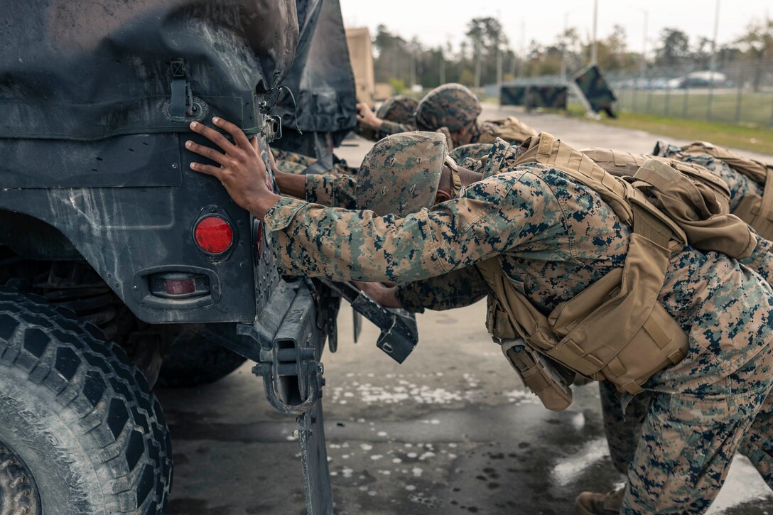 Marines push a vehicle during a competition.