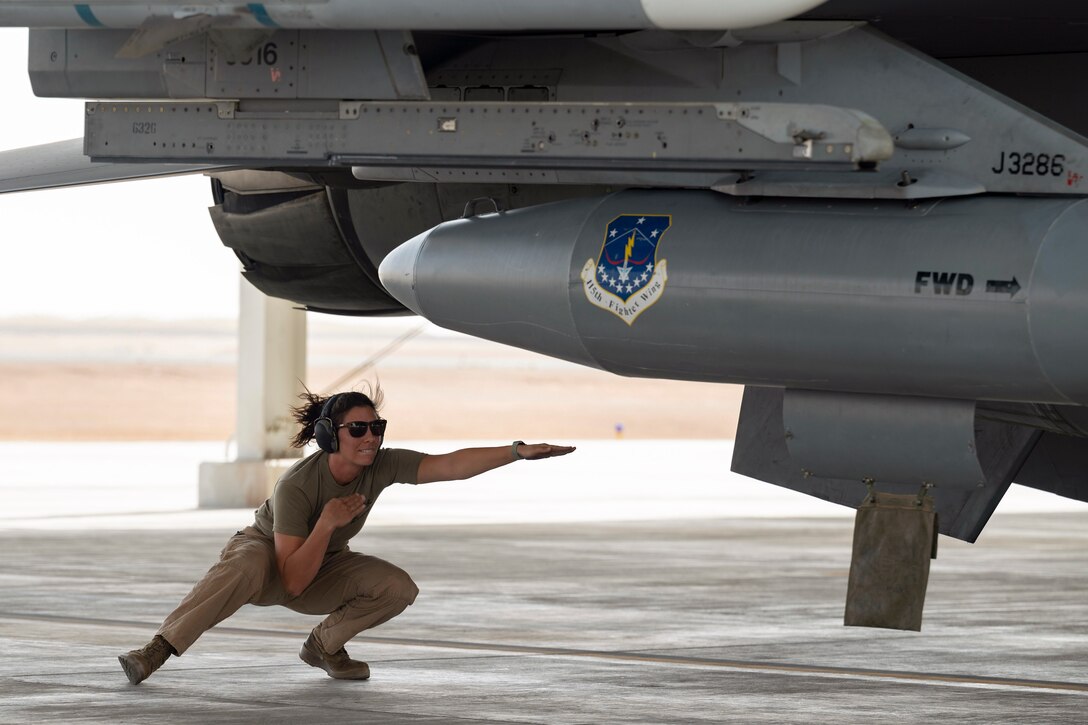 An airman directs an aircraft parked on the tarmac.