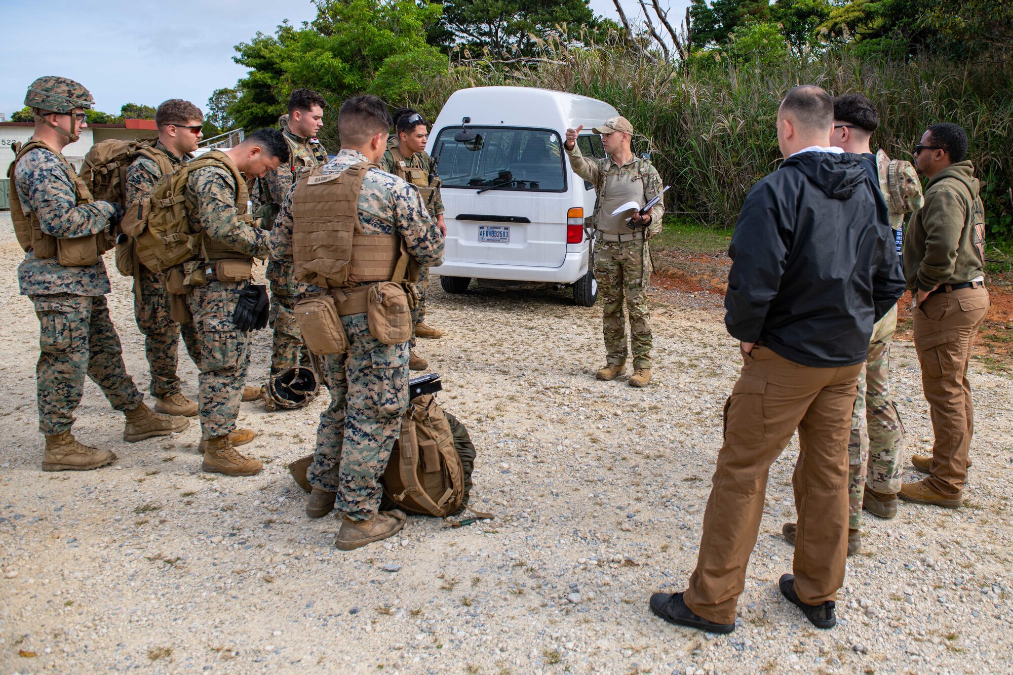 A group of airmen and marines gather around a SERE operative to discuss the plans for the exercise.