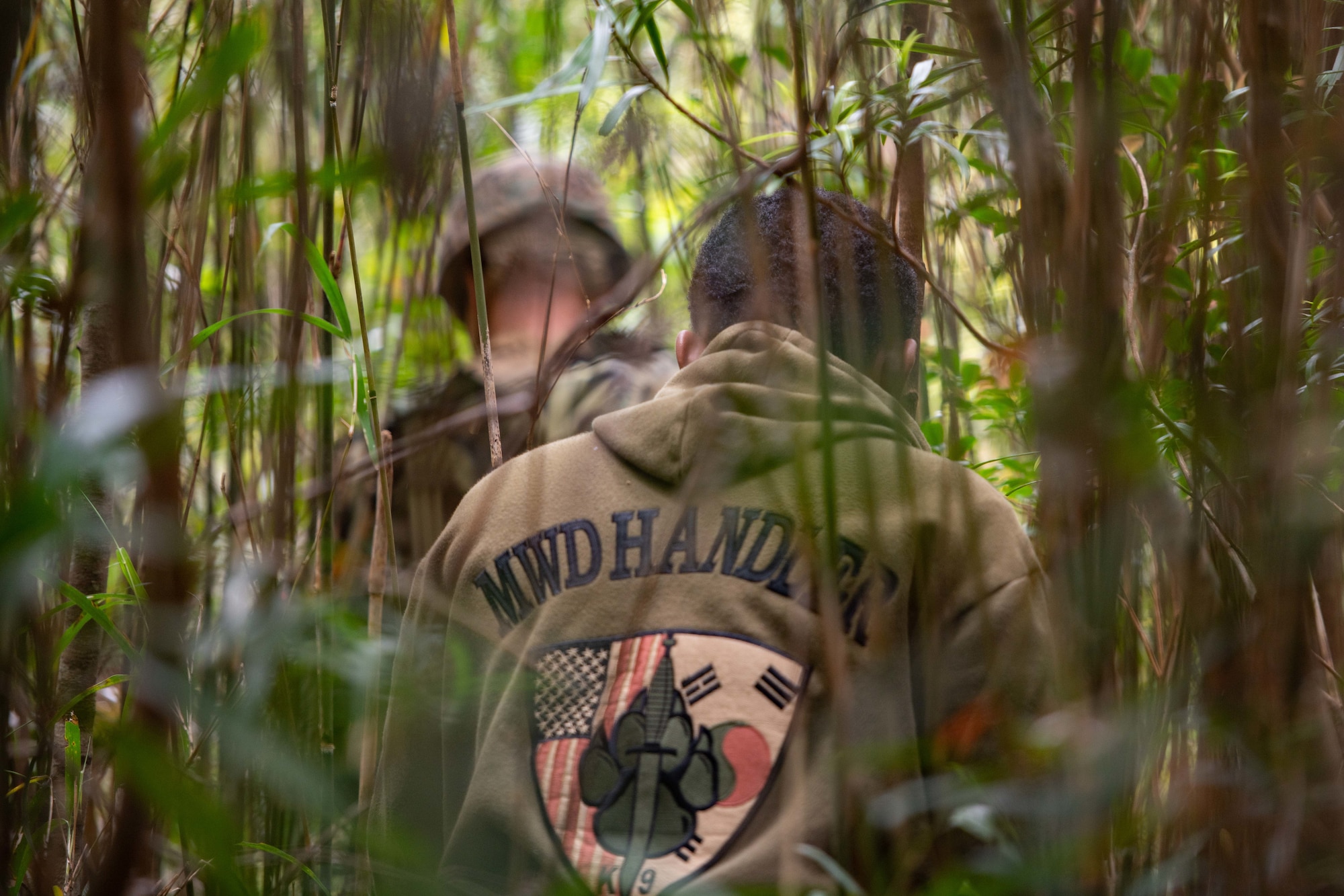 An airman follows a marine through the jungle