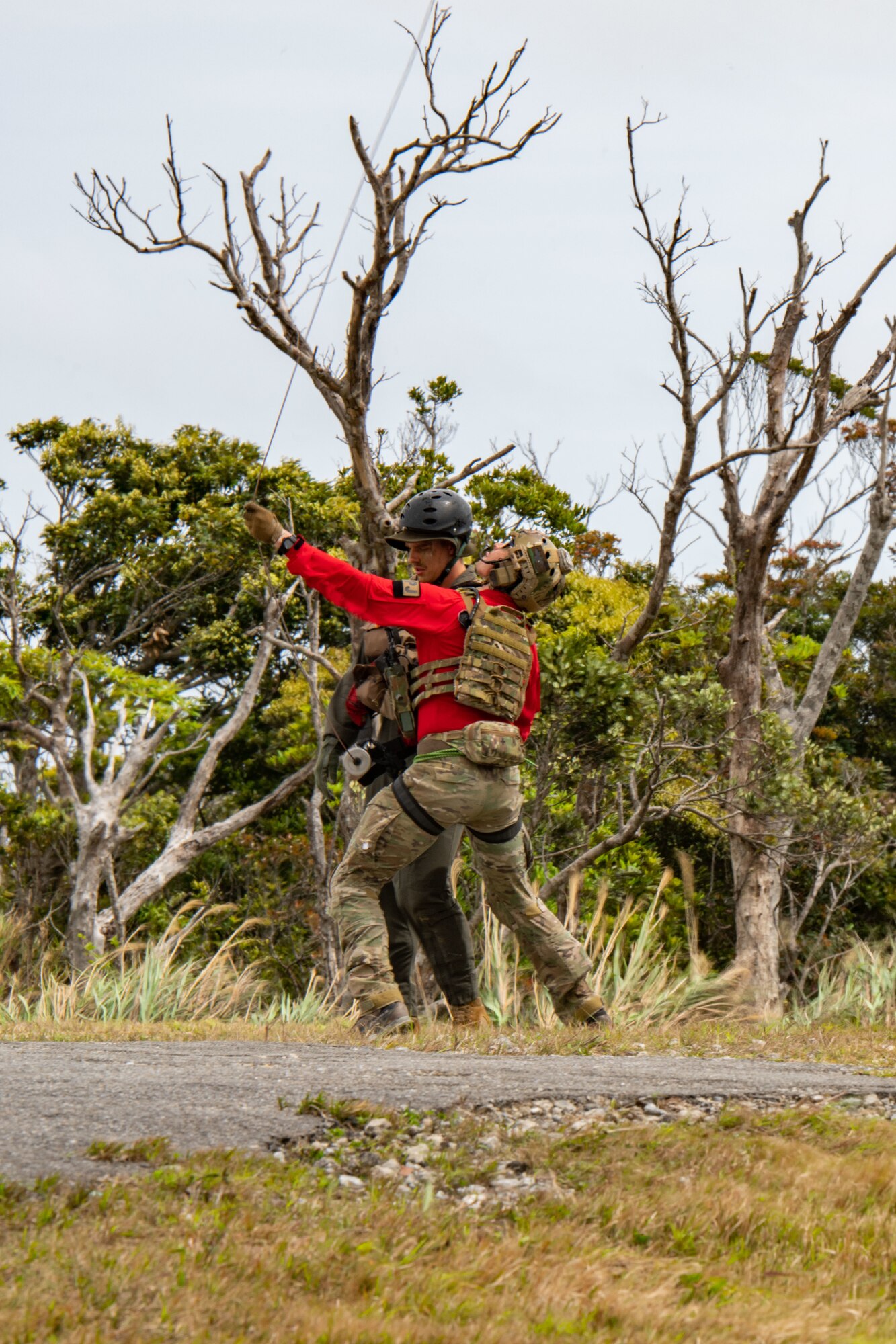 Two airmen test a line that will hoist them up to a helicopter from out of the jungle