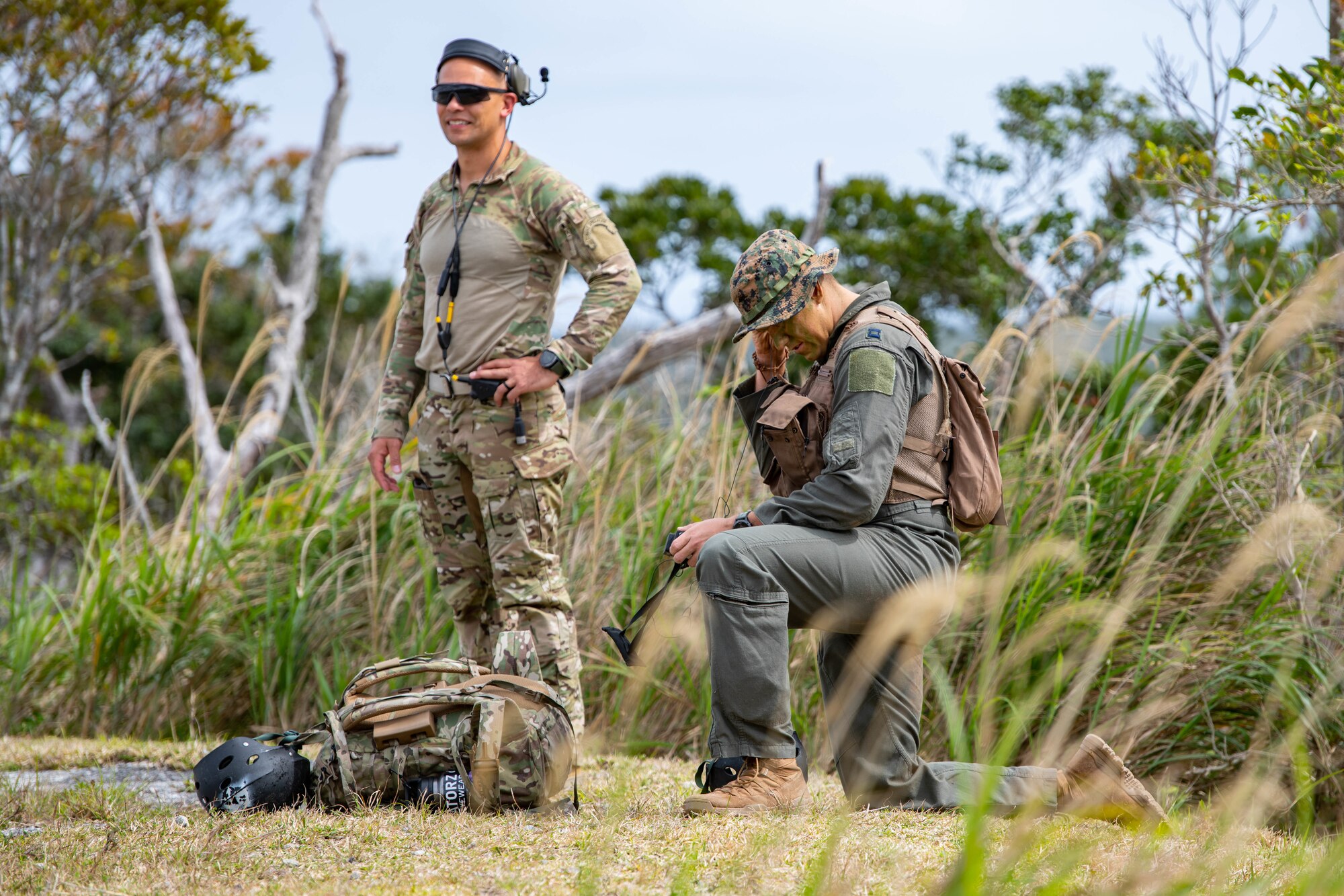 Two airmen radio to a helicopter for extraction from the jungle