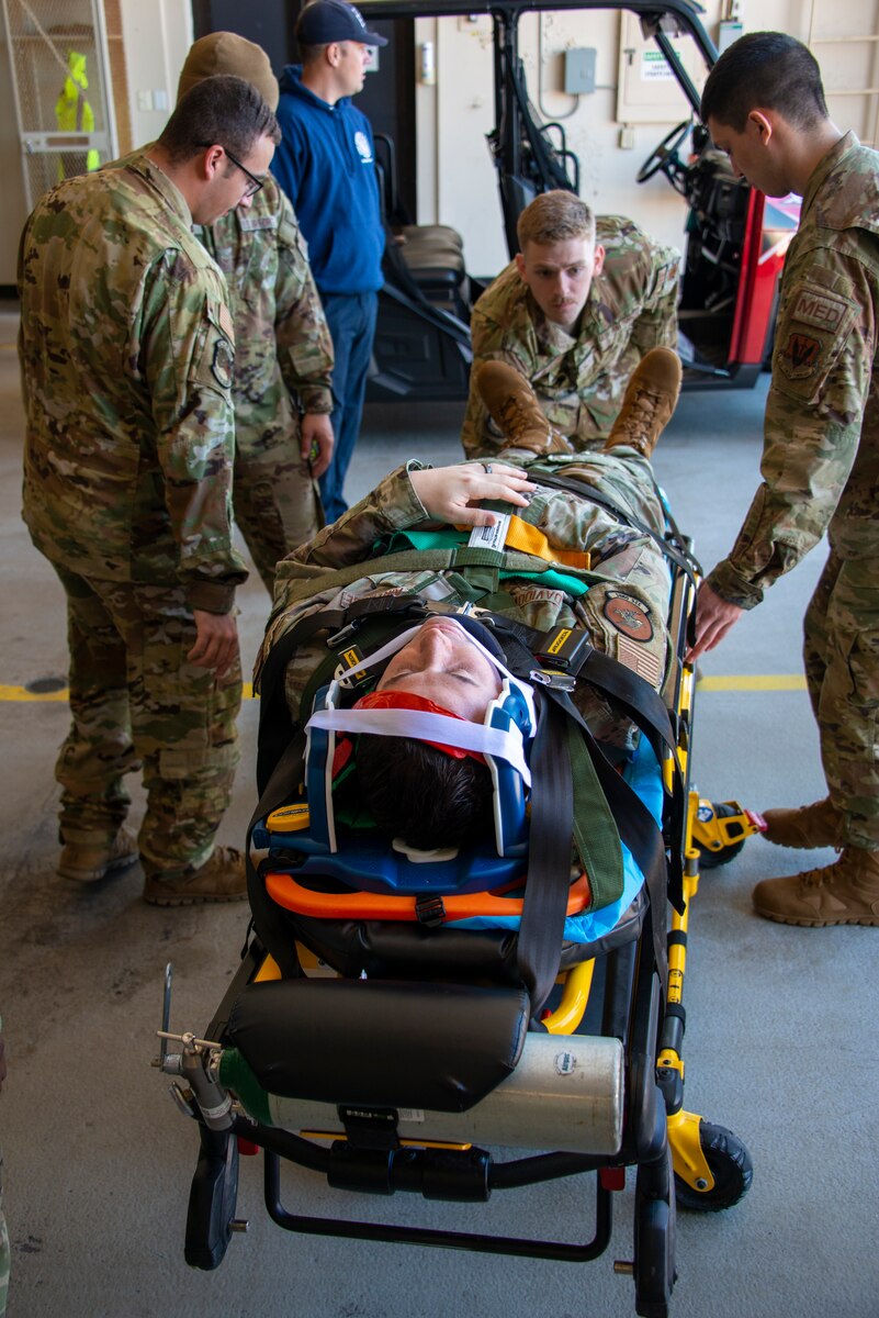 Airmen secure a simulated patient to a backboard