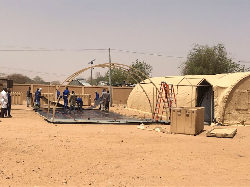 Nigerien workers build a mobile field hospital financed by the U.S. Africa Command through the Overseas Humanitarian, Disaster Assistance, and Civic Aid program in Agadez, Niger, March 22, 2022. U.S. subject matter experts taught Nigerien workers how to construct, maintain, de-construct, and move the mobile hospital. The $1.6 million, 4,592 square-foot mobile field hospital increases Agadez Regional Hospital’s capacity by an additional 30 beds, complete with the medical tools and resources to care for the 670,000-person community and surrounding areas. (U.S. Army courtesy photo by Staff Sgt. Peter Maenner)