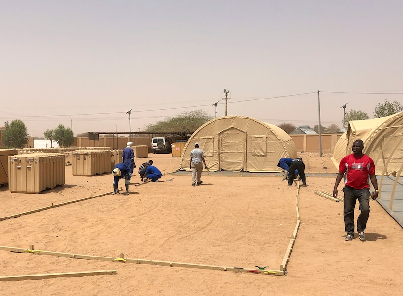 Nigerien workers build a mobile field hospital financed by the U.S. Africa Command through the Overseas Humanitarian, Disaster Assistance, and Civic Aid program in Agadez, Niger, March 22, 2022. U.S. subject matter experts taught Nigerien workers how to construct, maintain, de-construct, and move the mobile hospital. The $1.6 million, 4,592 square-foot mobile field hospital increases Agadez Regional Hospital’s capacity by an additional 30 beds, complete with the medical tools and resources to care for the 670,000-person community and surrounding areas. (U.S. Army courtesy photo by Staff Sgt. Peter Maenner)