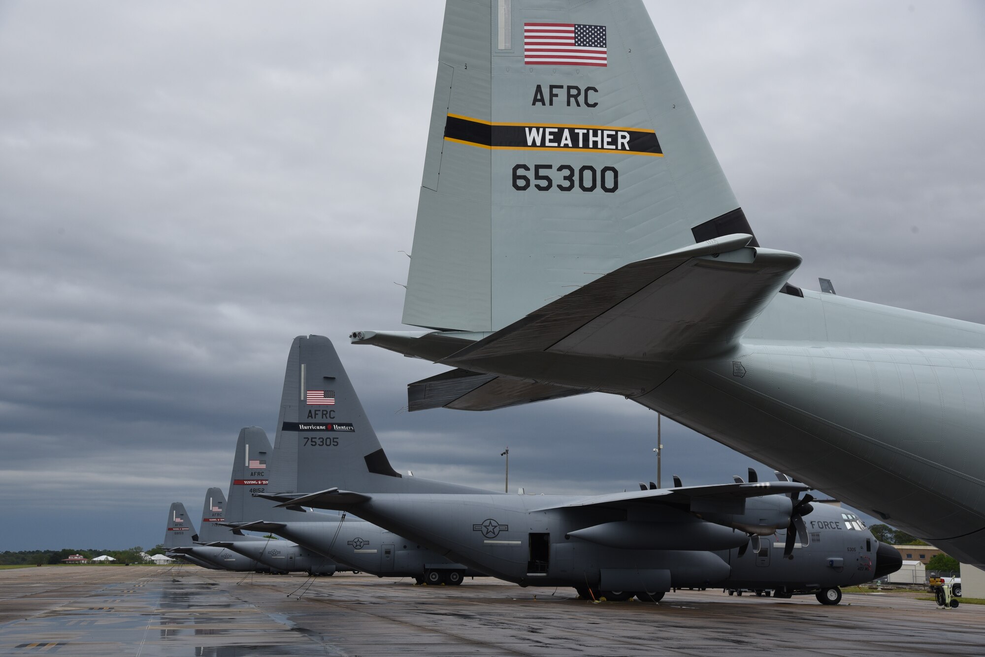 Tail fins of the new shiny gray paint scheme with vintage 'Weather' tail marking on WC-130J next to tactical gray version.