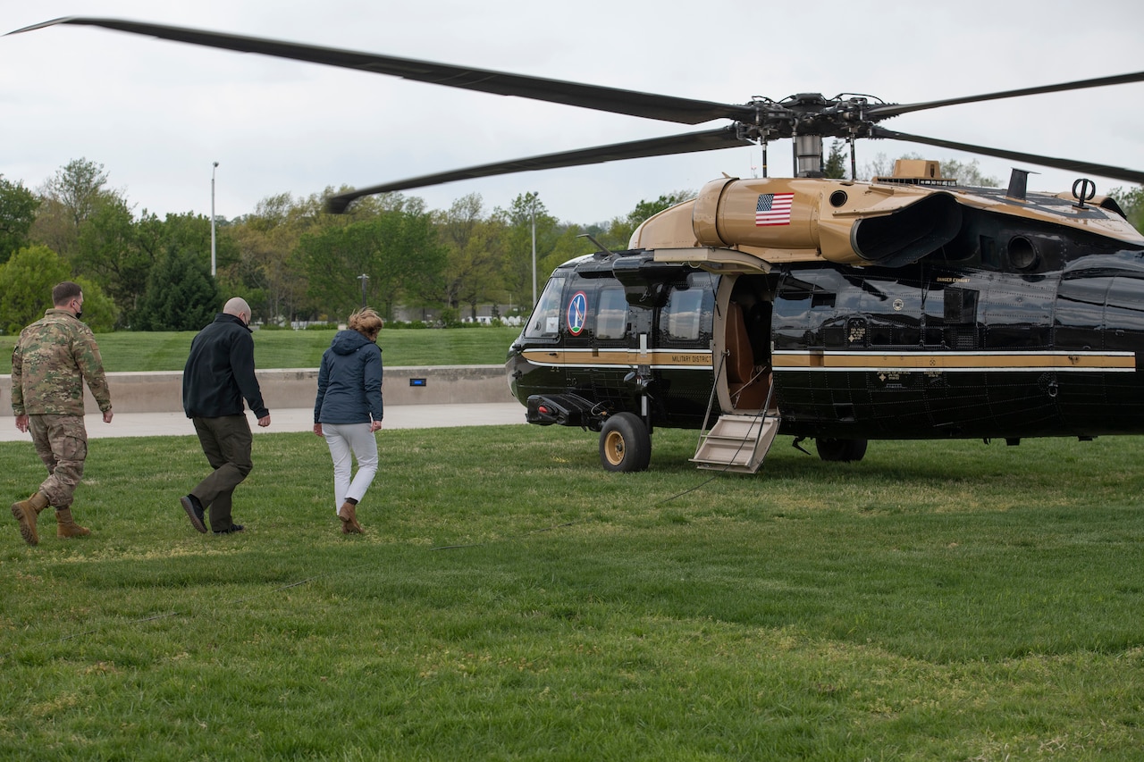 A woman walks toward a helicopter followed by two men.