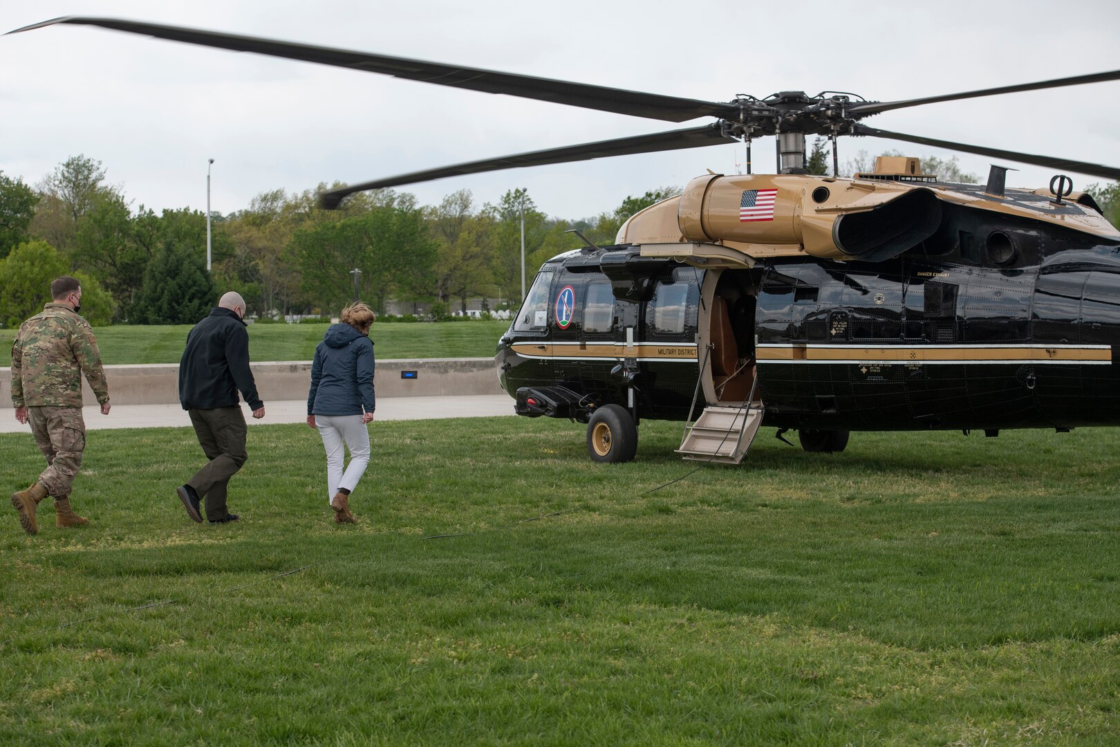 A woman walks toward a helicopter followed by two men.