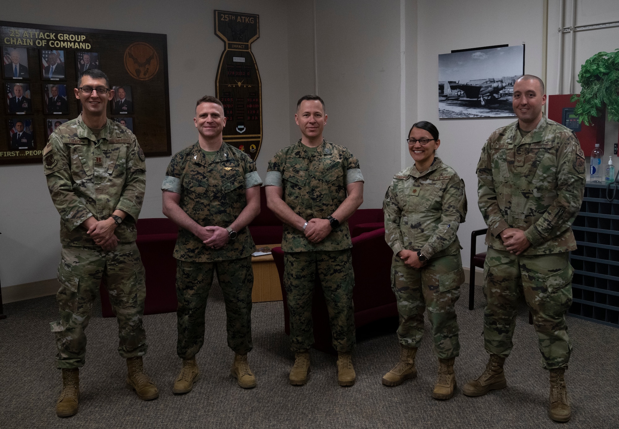 Two marines take a group photo with three Airmen