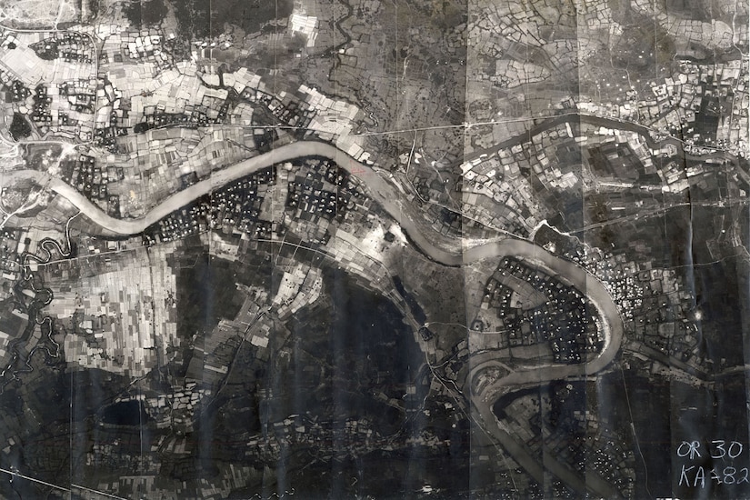 An aerial view of a winding river amid various encampments.