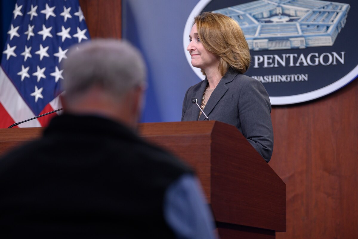 A woman stands at a lectern.