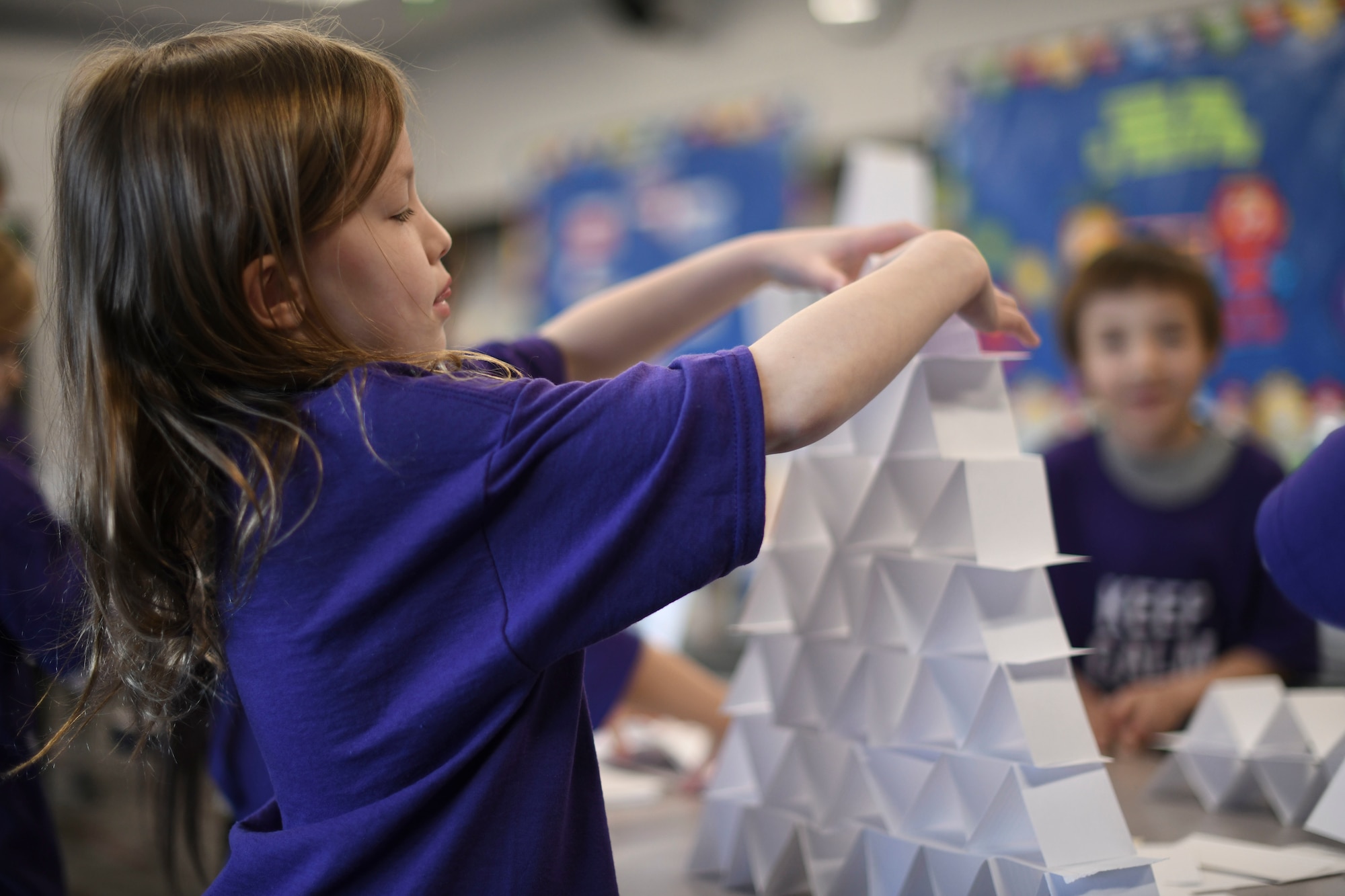 A student makes a tower out of paper.