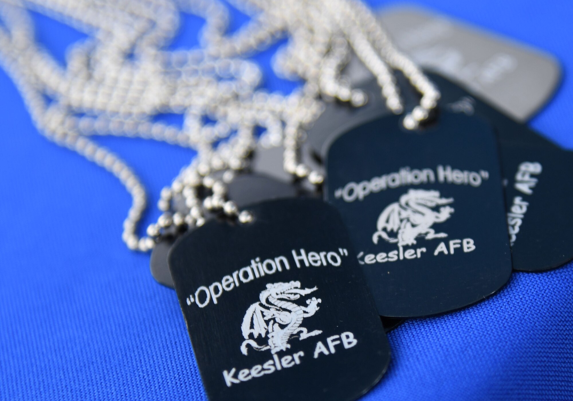 Operation Hero dog tags are on display during Operation Hero at Keesler Air Force Base, Mississippi, April 2, 2022. The event, hosted by the Airman and Family Readiness Center in recognition of the Month of the Military Child, gave military children a glimpse into the lives of deployed military members. Children received Operation Hero dog tags and t-shirts as they made their way through a mock deployment line as well as the opportunity to experience medical triage demonstrations, military working dog demonstrations and have their faces painted. (U.S. Air Force photo by Kemberly Groue)