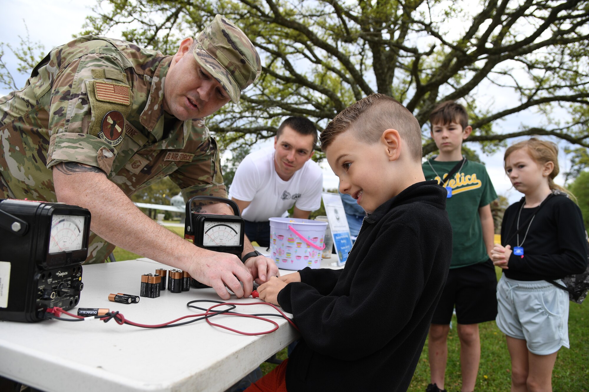 U.S. Air Force Master Sgt. Joseph Stone, 335th Training Squadron training flight chielf, provides a battery voltage demonstration to Asher del Rio, son of Capt. Nathan del Rio, 81st Operational Medical Readiness Squadron warrior clinic element leader, during Operation Hero at Keesler Air Force Base, Mississippi, April 2, 2022. The event, hosted by the Airman and Family Readiness Center in recognition of the Month of the Military Child, gave military children a glimpse into the lives of deployed military members. Children received Operation Hero dog tags and t-shirts as they made their way through a mock deployment line as well as the opportunity to experience medical triage demonstrations, military working dog demonstrations and have their faces painted. (U.S. Air Force photo by Kemberly Groue)