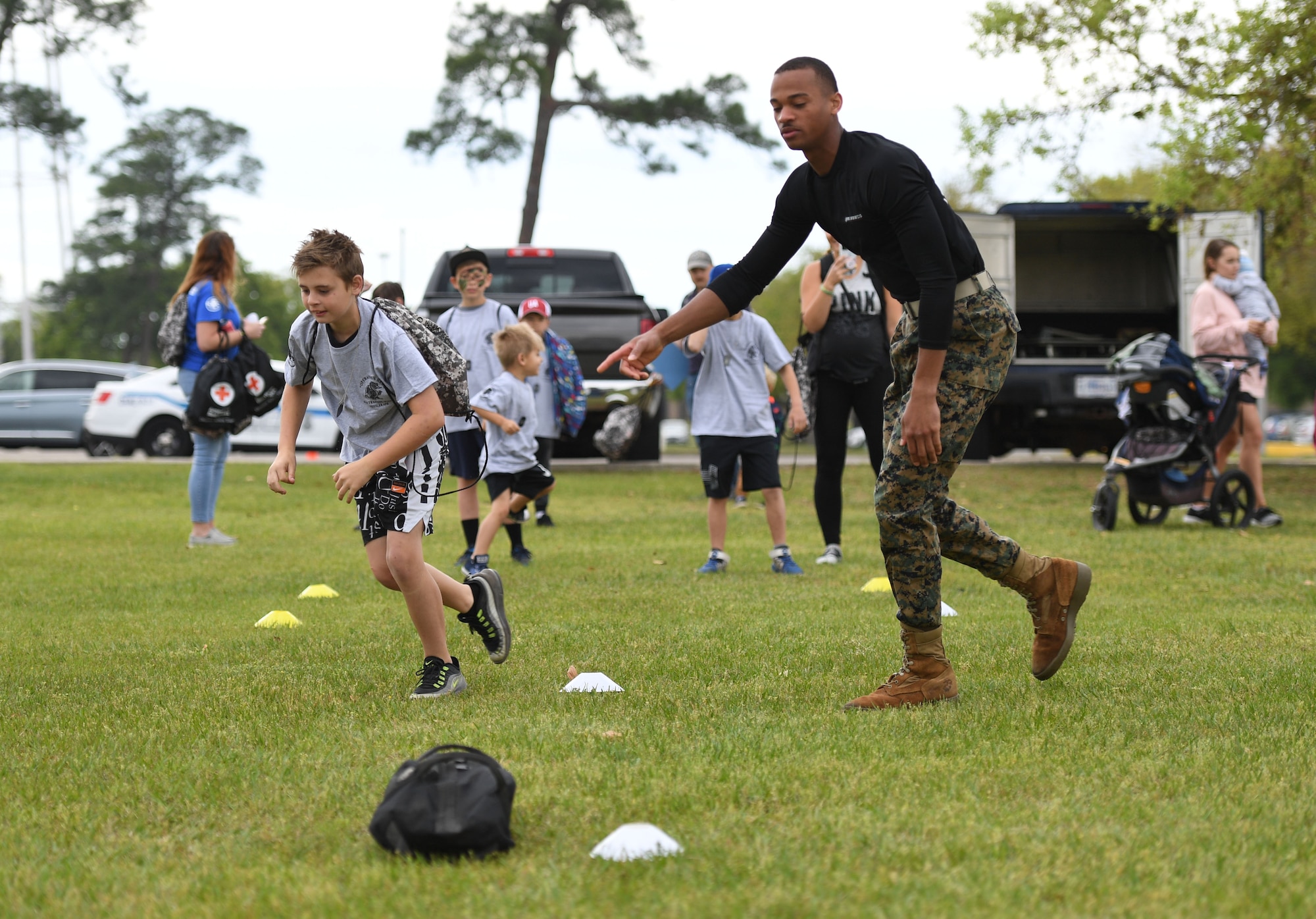 U.S. Marine Private First Class Moises Gomes, Keesler Marine Detachment student, and Espen Padgett, son of Tech. Sgt. Derek Padgett, 334th Training Squadron instructor, participate in an obstacle course during Operation Hero at Keesler Air Force Base, Mississippi, April 2, 2022. The event, hosted by the Airman and Family Readiness Center in recognition of the Month of the Military Child, gave military children a glimpse into the lives of deployed military members. Children received Operation Hero dog tags and t-shirts as they made their way through a mock deployment line as well as the opportunity to experience medical triage demonstrations, military working dog demonstrations and have their faces painted. (U.S. Air Force photo by Kemberly Groue)