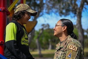 An airman talks with a child at a playground.