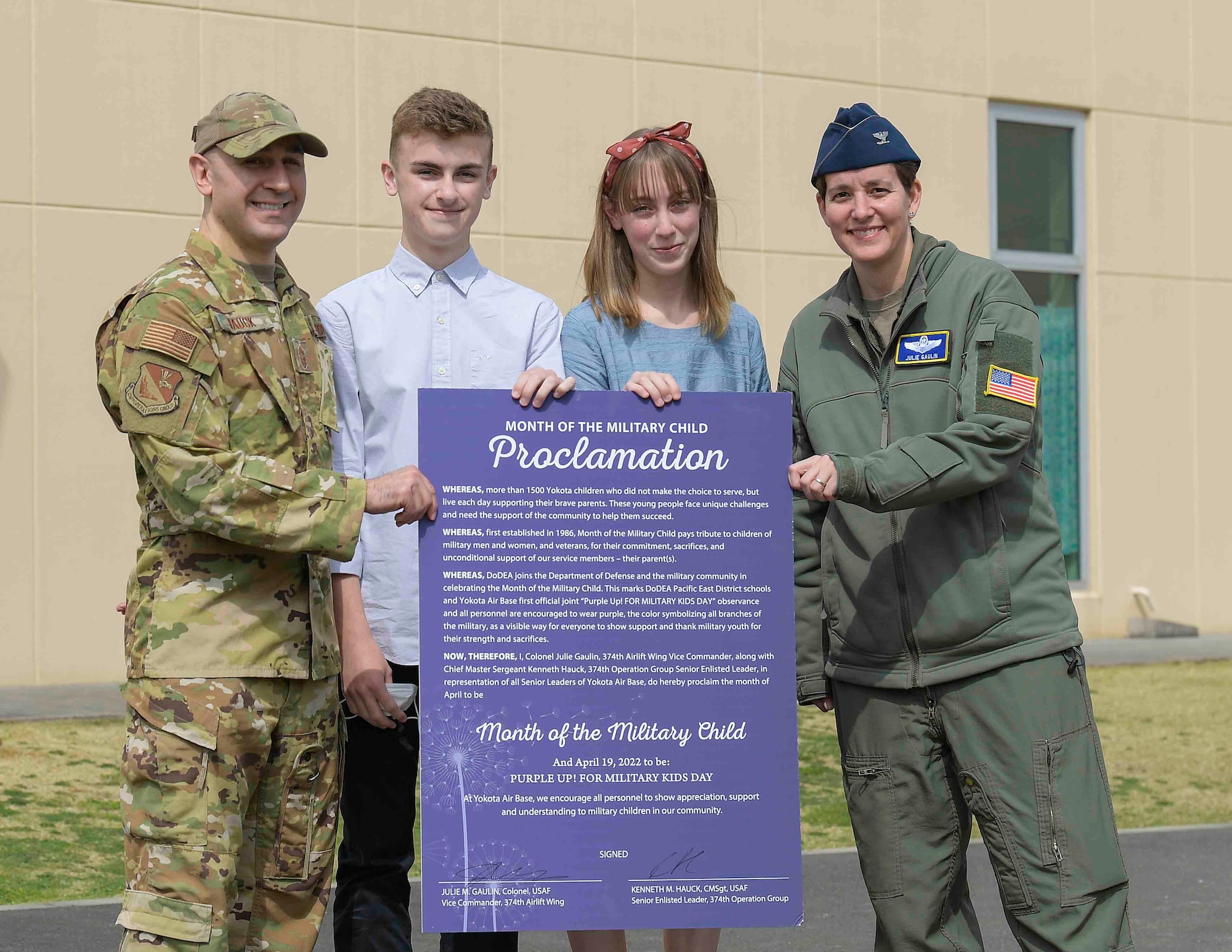 Chief Master Sgt. Kenneth Hauck, left, 374th Operations Group command chief, and Col. Julie Gaulin, right, 374th Airlift Wing vice commander, pose for a photo with Yokota Middle School student after a Month of the Military Child proclamation event at Yokota Air Base, Japan, April 7, 2022.