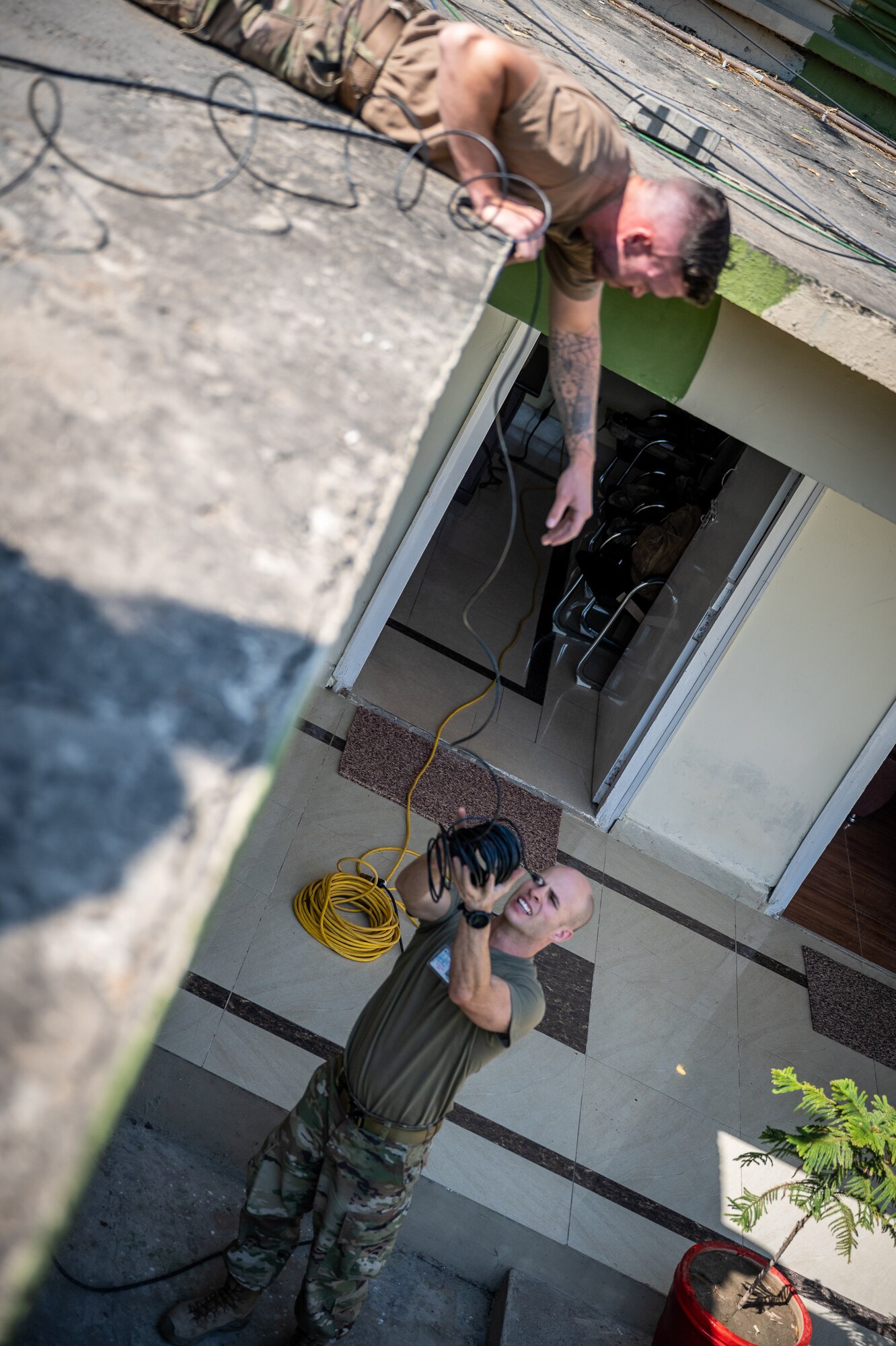 Staff Sgt. Benjamin Wilson, 332d Expeditionary Communications Squadron network infrastructure supervisor, drops a network cable to Senior Airman Justin Malsbury, U.S. Air Forces Central contingency communications technician, while setting up a communications fly-away kit at a Pakistan operational air force base, Feb. 27, 2022. The kit allowed U.S. Air Force members from across the Air Forces Central area of responsibility to manage communications while supporting Falcon Talon 2022, an Agile Combat Employment operation and the first bilateral training event between the United States and Pakistan since 2019. (U.S. Air Force photo by Master Sgt. Christopher Parr)