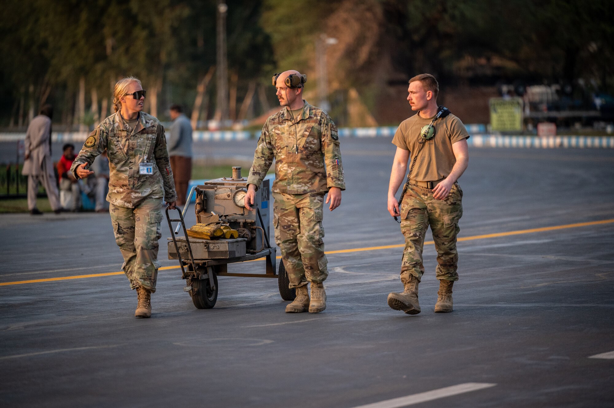 Master Sgt. Cassandra Moore, 55th Expeditionary Fighter Generation Squadron production superintendent, walks with Staff Sgt. Hogan Hutchins, 55EFGS avionics craftsman, and Senior Airman Keagan Kinser, 55EFGS avionic journeyman, to pre-stage a hydraulic cart for aircraft launch and recovery during Falcon Talon 2022 at a Pakistan operational air force base, Feb. 26, 2022. This Agile Combat Employment operation is the first bilateral training event between the United States and Pakistan since 2019. (U.S. Air Force photo by Master Sgt. Christopher Parr)