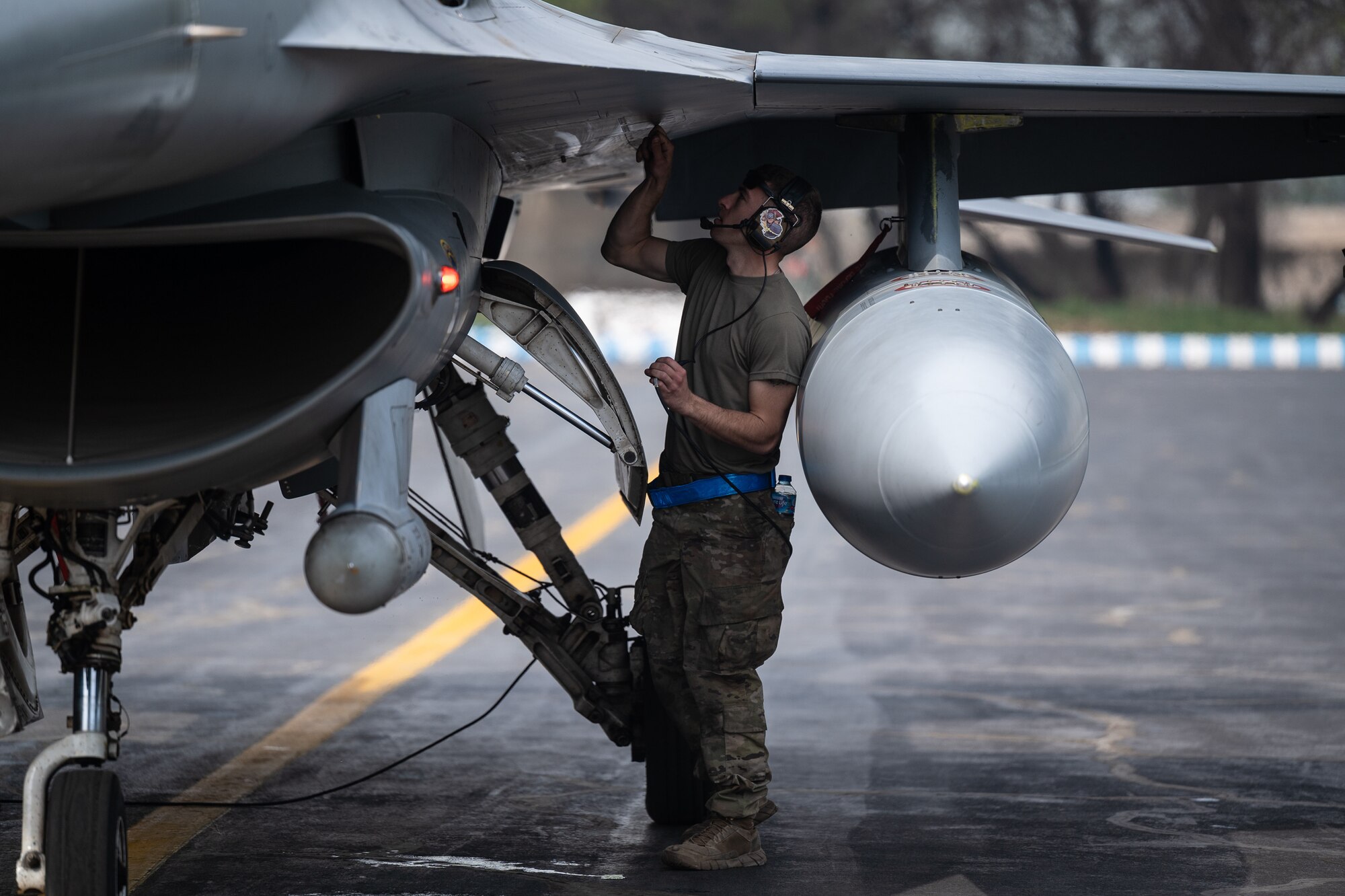 Tech. Sgt. Andrew Burke, 55th Expeditionary Fighter Generation Squadron flight line expeditor, conducts servicing checks on a U.S. Air Force F-16 Fighting Falcon aircraft prior to launching a training sortie from a Pakistan operational air force base, March 2, 2022, during Falcon Talon 2022. This Agile Combat Employment operation is the first bilateral training event between the United States and Pakistan since 2019. (U.S. Air Force photo by Master Sgt. Christopher Parr)