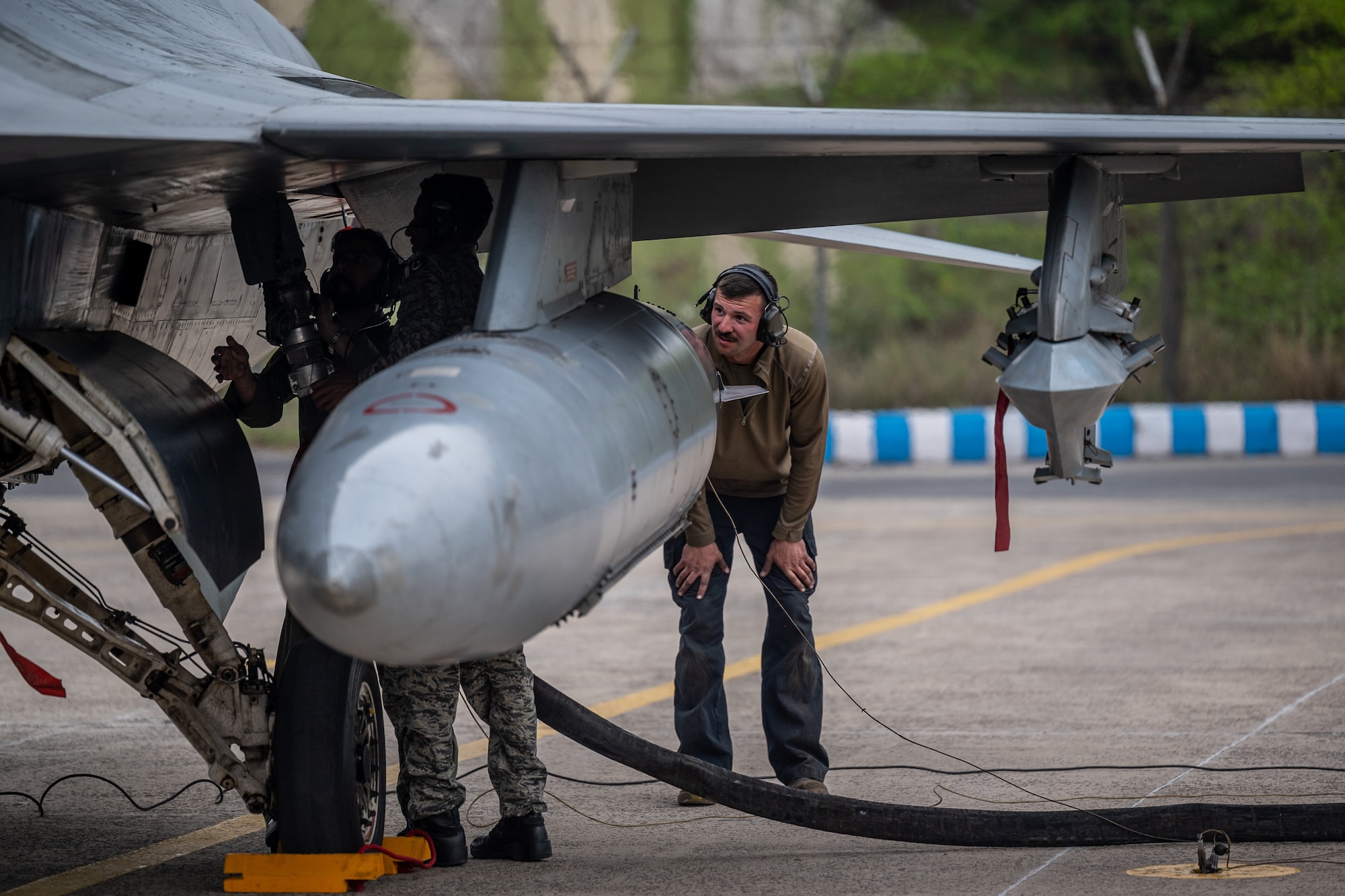 Senior Airman Clay Fulfer, 55th Expeditionary Fighter Generation Squadron dedicated crew chief, watches as several Pakistan Air Force engineer members perform a rapid refuel of a PAF F-16 aircraft during Falcon Talon 2022 Integrated Combat Turnaround training, March 2, 2022.  ICTs are rapid re-arming and refueling of aircraft with engines still running, reducing ground time to quickly resume air operations. The Agile Combat Employment operation, held Feb. 28 - March 4, 2022, is the first bilateral training event between the two countries since 2019. (U.S. Air Force photo by Master Sgt. Christopher Parr)