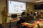 Illinois Air National Guard 1st Lt. Paul Murley, cyber range project officer, left, and Illinois Air Army National Guard 1st. Lt. Christopher Muenster, right, explain the uses of the new 183d Joint Cyber Center of Excellence Cyber Range at the 183d Wing, Springfield, Illinois, April 2, 2022.