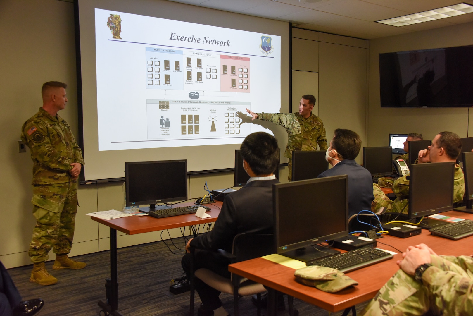Illinois Air National Guard 1st Lt. Paul Murley, cyber range project officer, left, and Illinois Air Army National Guard 1st. Lt. Christopher Muenster, right, explain the uses of the new 183d Joint Cyber Center of Excellence Cyber Range at the 183d Wing, Springfield, Illinois, April 2, 2022.