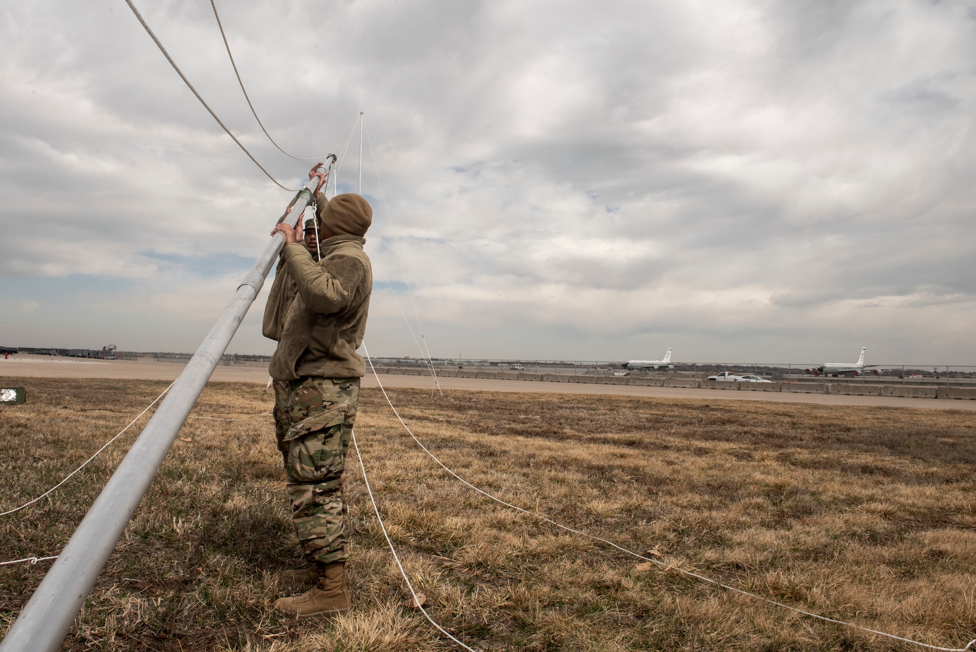 Airmen lift a satellite pole.