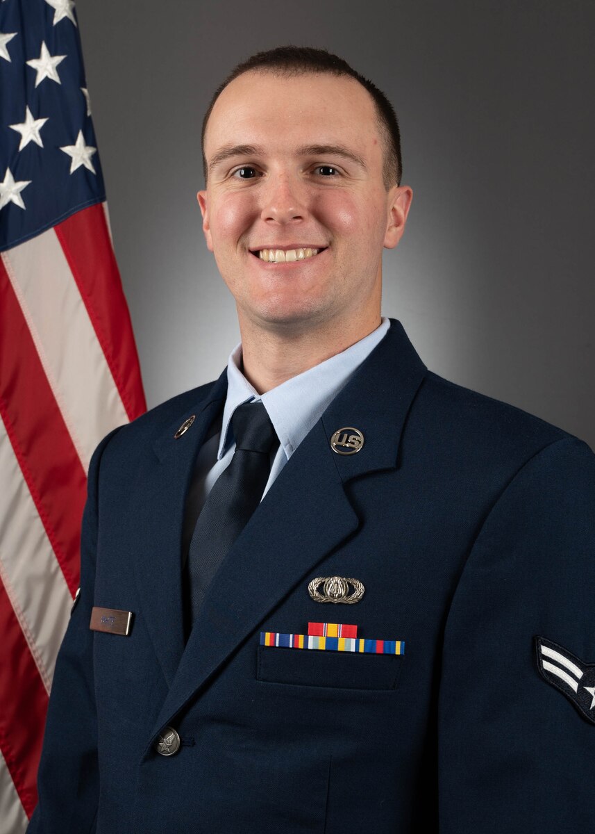 Official photo of A1C Sean White in Service Dress, US Flag in background.