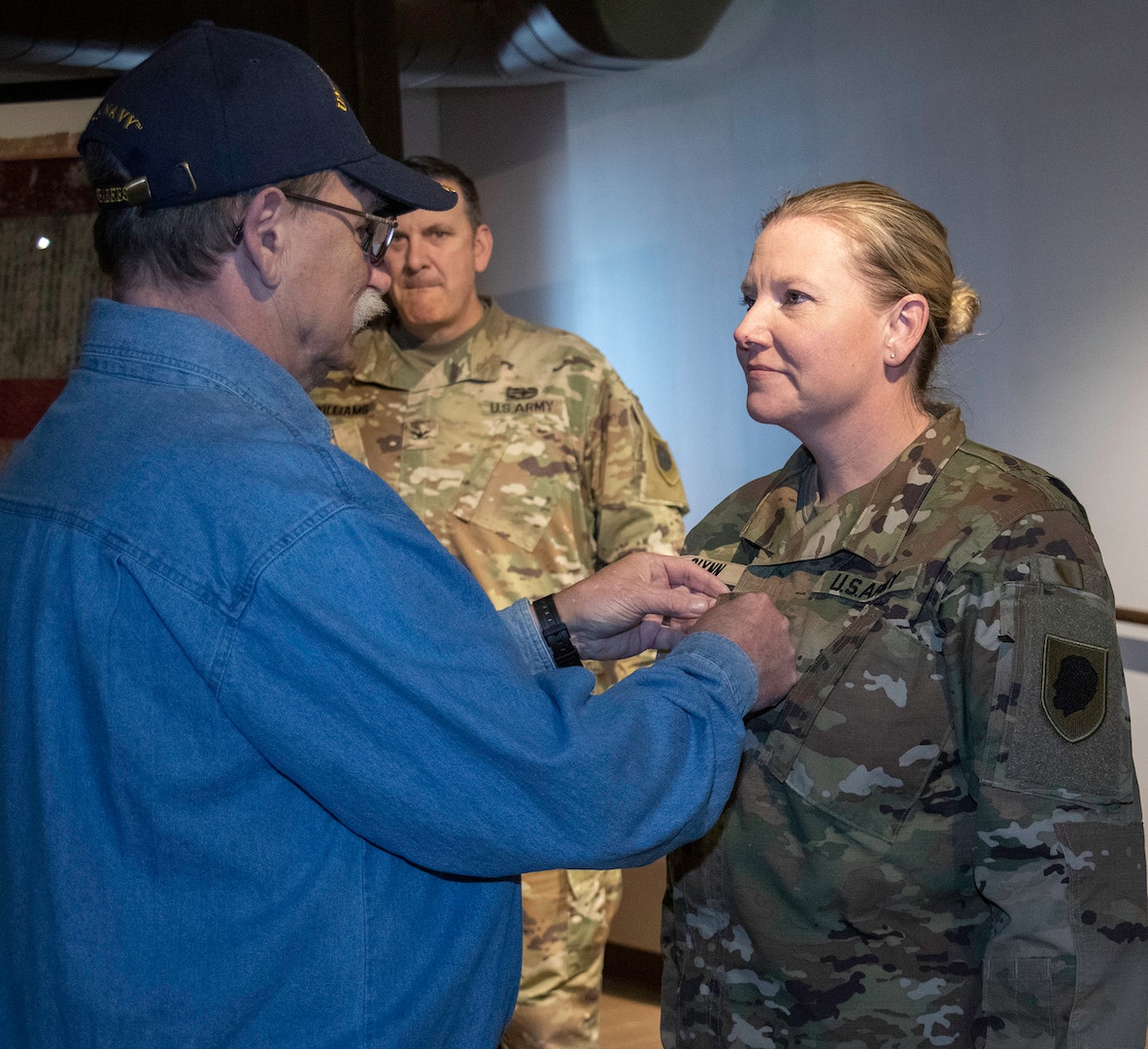 Tim Pettyjohn, father of newly promoted CW4 Lindsay Glynn, secures her new rank during a promotion ceremony March 25 at the Illinois State Military Museum in Springfield, Illinois.