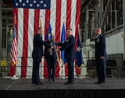 Four Airmen on stage passing around the organizational colors.