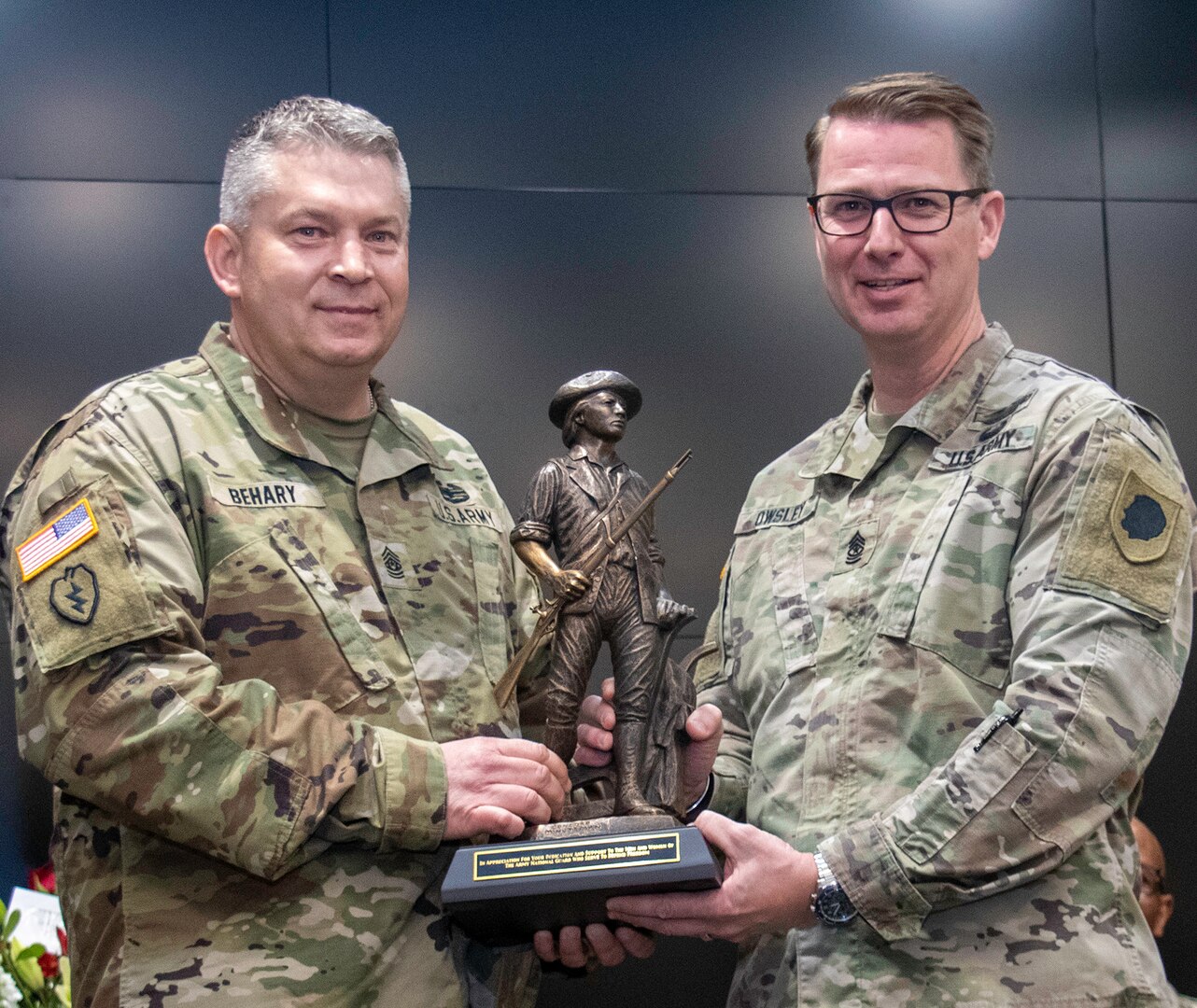 Sgt. Maj. David Owsley, of Forsyth, Illinois, Plans, Operations and Training sergeant major, receives a Minute Man statue from Command Sgt. Maj. Michael Behary, of Sherman, State Command Sergeant Major, in honor of his retirement after nearly 33 years of service in the Illinois Army National Guard.