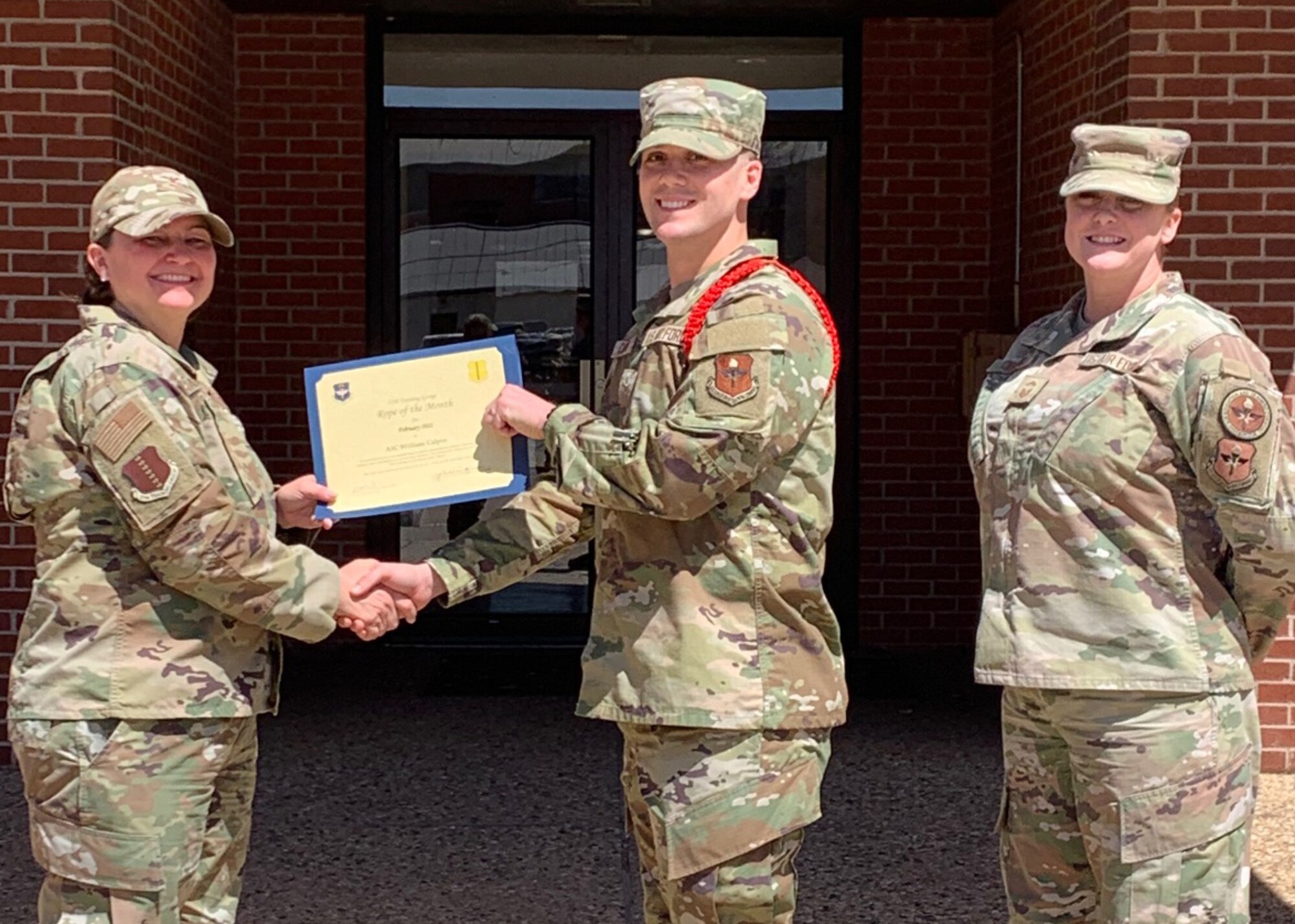 U.S. Air Force Col. Angelina Maguinness, 17th Training Group commander, and Senior Master Sgt. Heather Celano, 313th Training Squadron senior enlisted leader, presents Airman 1st Class William Calpin, 316th Training Squadron student, the 17th TRG Rope of the Month award for February 2022, Goodfellow Air Force Base, Texas, April 4, 2022. The 316th TRS is responsible for training, developing, and inspiring intelligence, surveillance, and reconnaissance cryptologic leaders. (Courtesy photo)