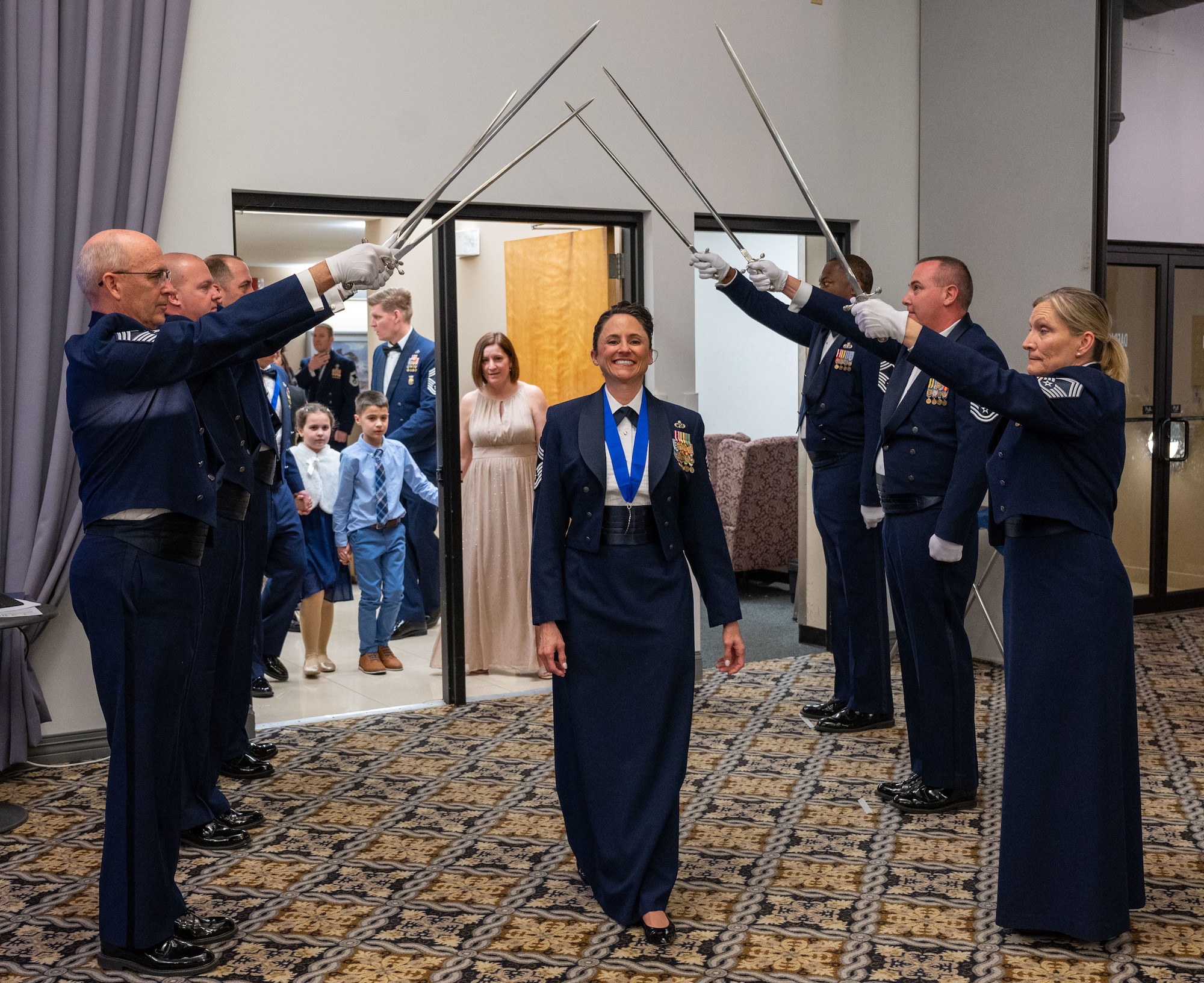 Chief Master Sgt. Rhonda Gambill, 46th Aerial Port Squadron senior enlisted leader, enters the ballroom under a saber detail during the 2022 Chief Induction ceremony at Dover Air Force Base, Delaware, April 2, 2022. The rank of chief master sergeant is the highest enlisted rank in the Air Force, with only one percent of the enlisted force structure reaching it. (U.S. Air Force photo by Airman 1st Class Cydney Lee)