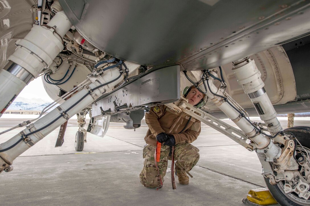 An airman kneels next to an aircraft.