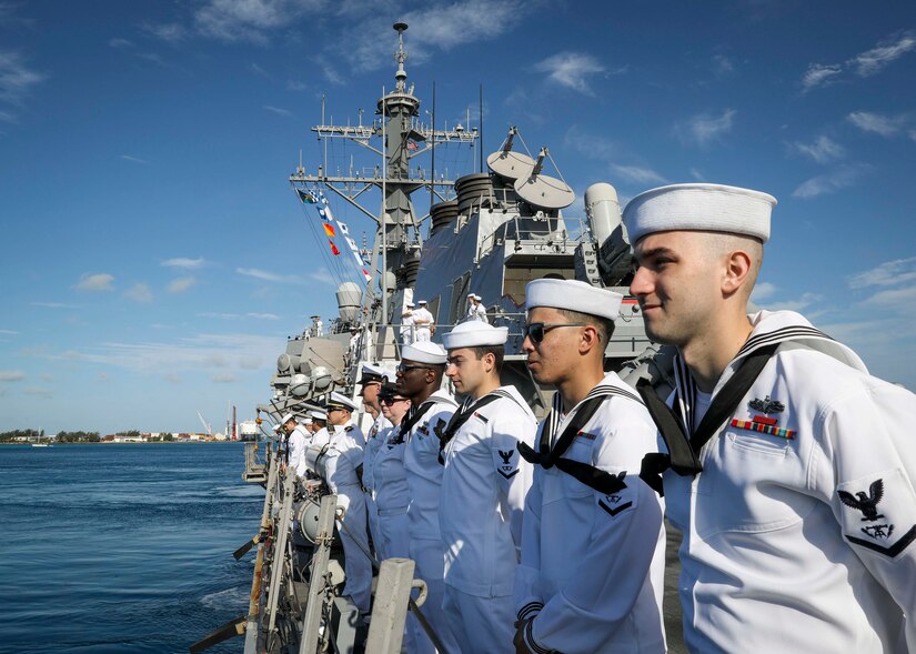 Sailors stand on a ship.