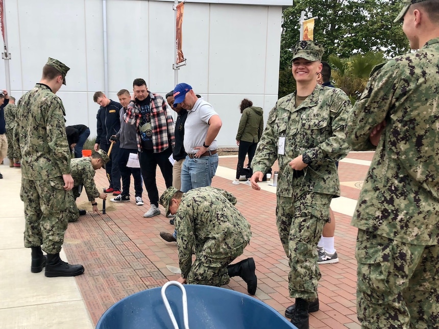 Volunteers from Center for Seabees and Facilities Engineering Chiefs Mess, and instructors and students from the Naval Construction Training Center Port Hueneme install commemorative bricks.