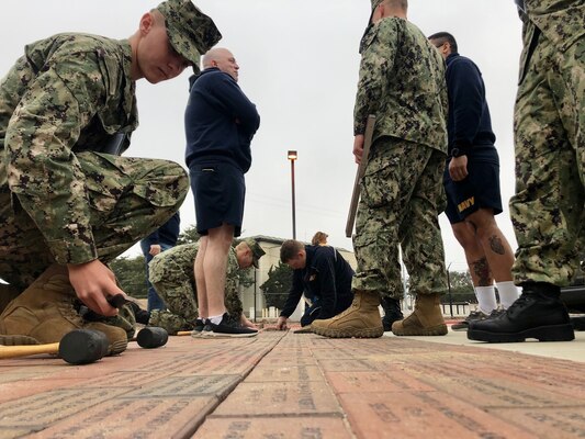 Volunteers from Center for Seabees and Facilities Engineering Chiefs Mess, and instructors and students from the Naval Construction Training Center Port Hueneme install commemorative bricks.