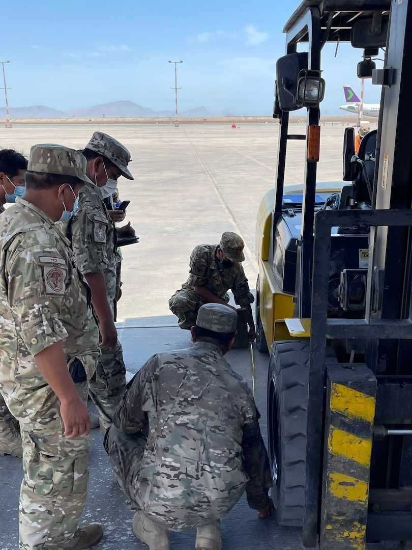 Peruvian Air Force Técnicos measure data to calculate a forklift's center of gravity March 1, 2022, at Callao Air Base, Lima, Peru. Air advisors spent most of the day teaching loadmaster and aerial port logistics as part of their tactical air mobility operations training for PERAF members. (Courtesy photo)