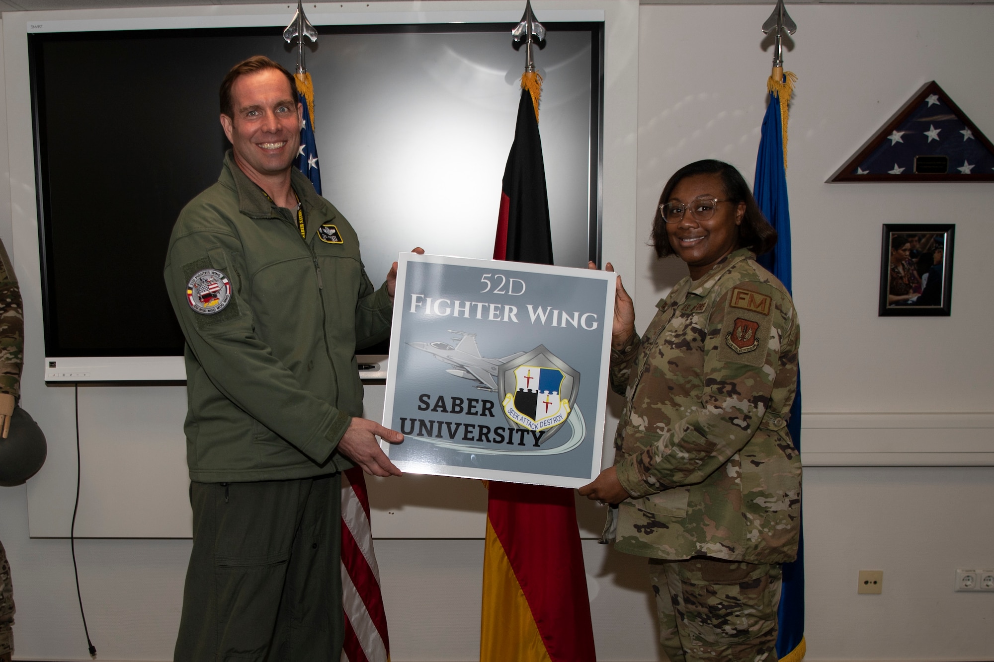 U.S. Air Force Col. Leslie Hauck, 52nd Fighter Wing commander, left, is presented the first Saber University sign by Staff Sgt. Sakiah Green, 52nd Comptroller Squadron financial operations supervisor, Apr. 4, 2022, on Spangdahlem Air Base, Germany.