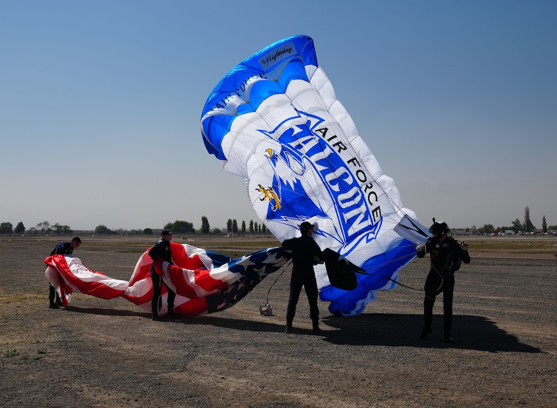 Air Force Academy Wings of Blue Parachute Team members assist Cadet First Class James Norkosky (right) by catching the American flag after his jump during Feria Internacional del Aire y del Espacio (FIDAE).
