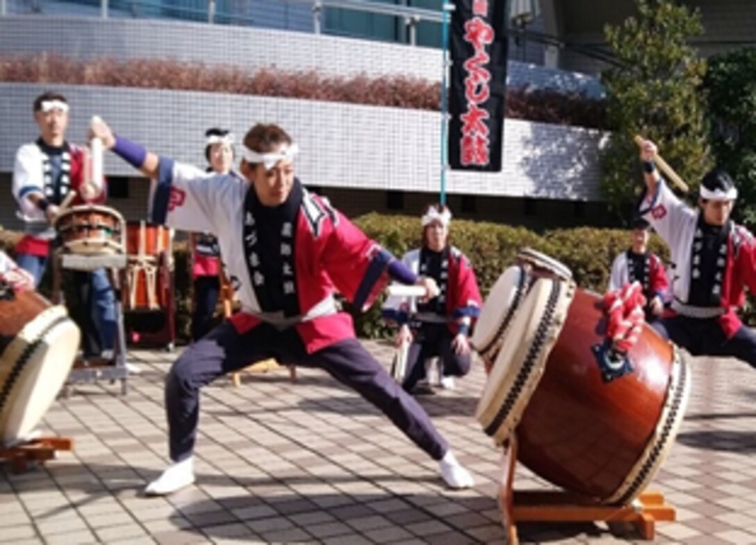 A woman prepares to strike a Japanese drum.