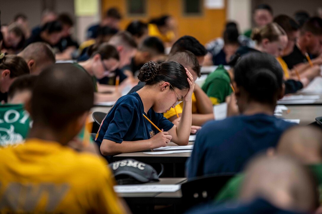 A room full of Navy cadets sit at desks and take tests.