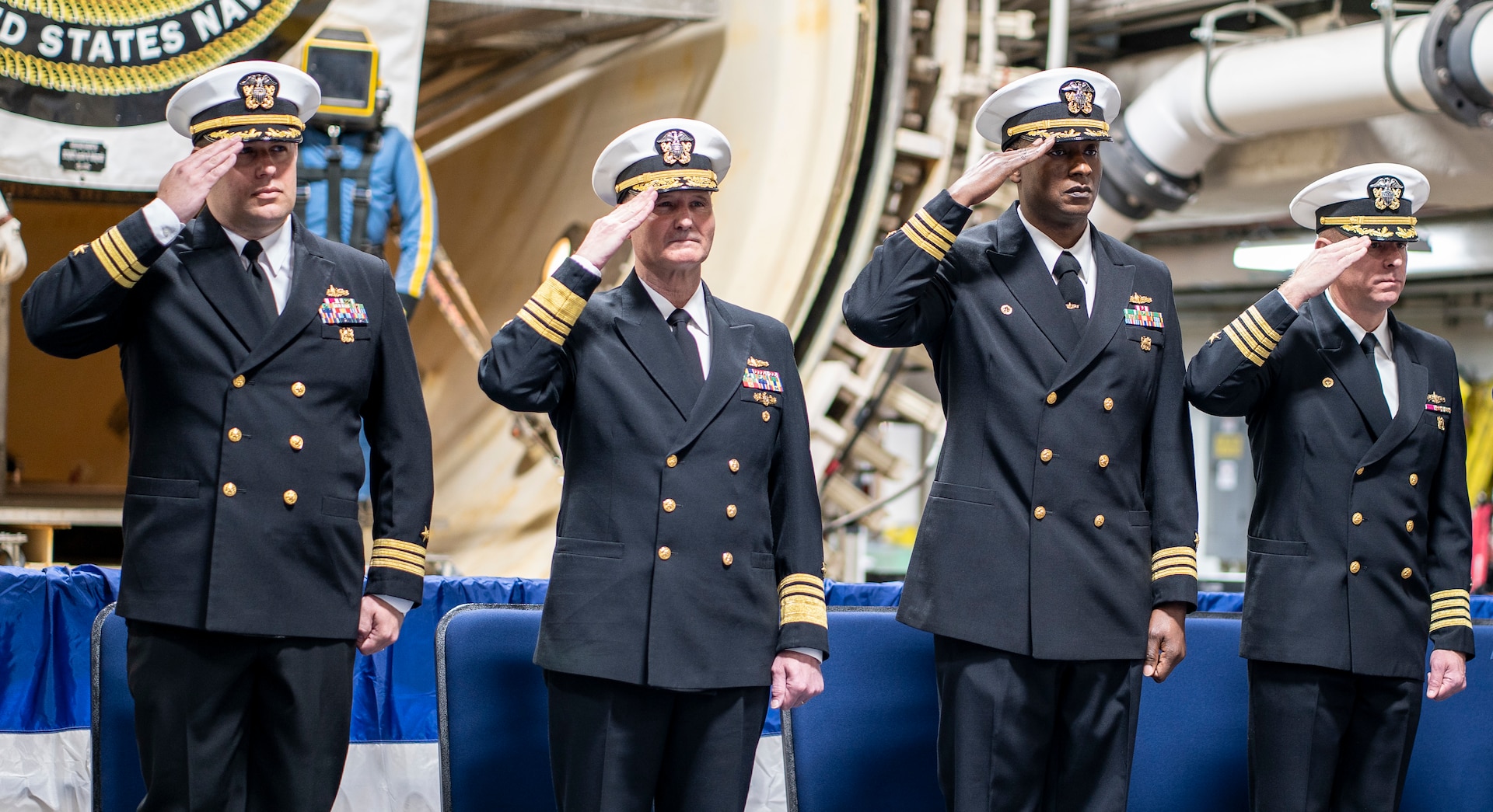 From left to right: CDR Dustin Cunningham, VADM William Galinis, CAPT (Sel) Kiah Rahming, and CAPT Jay salute the Ensign during the National Anthem.