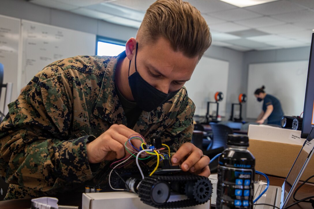 A Marine works with wiring as he builds a robot.